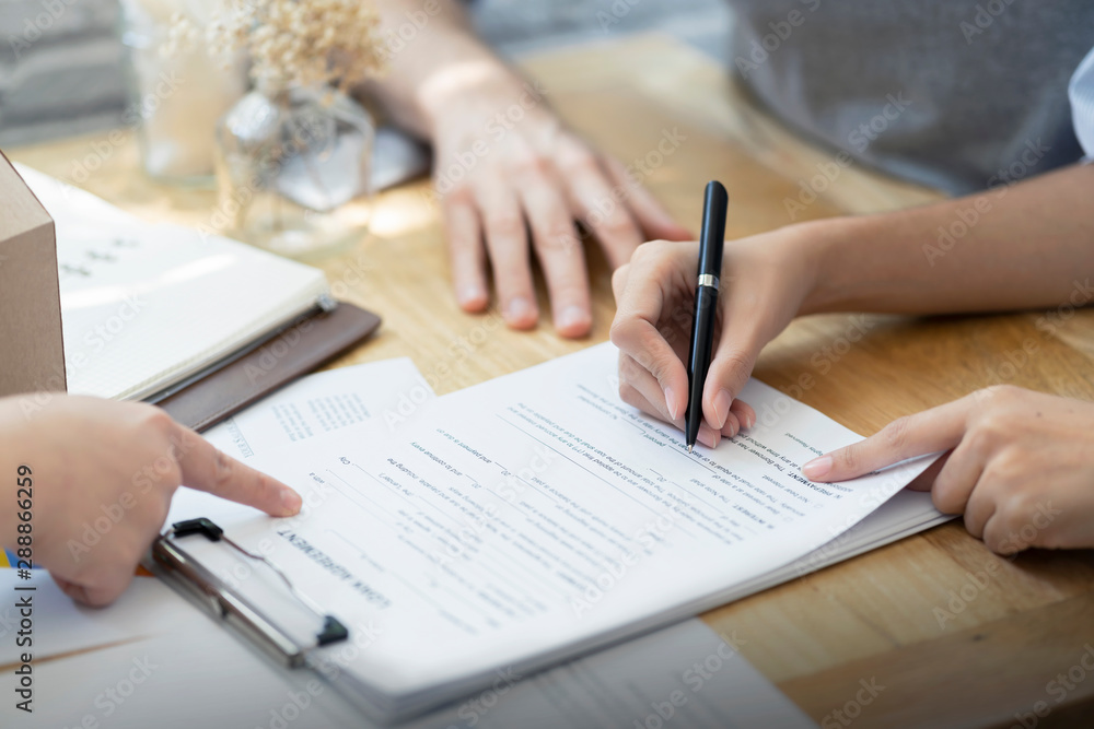 Woman putting signature on document loan contract, real estate purchase, hands of woman sale represent point document to sign, contract deals success business. Woman putting signature on document loan contract, real estate purchase, hands of woman sale represent point document to sign, contract deals success business.