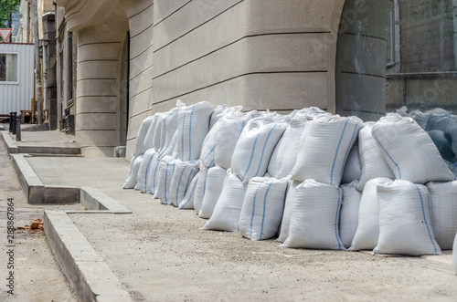 Lots of bags of cement or sand near the wall for building or laying tiles close up