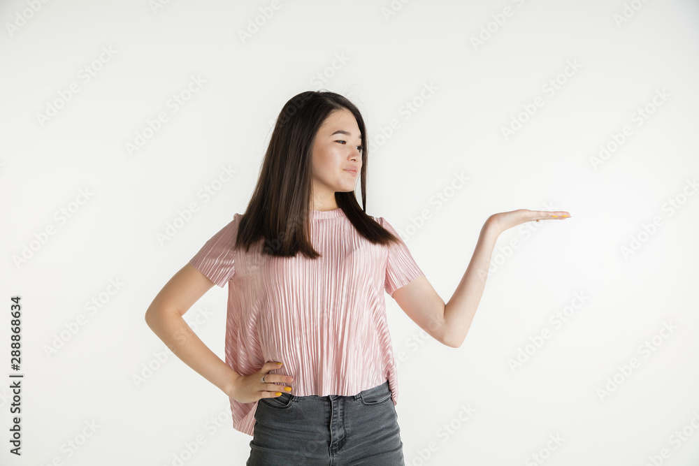 Beautiful female half-length portrait isolated on white studio background. Young emotional woman in casual clothes. Human emotions, facial expression concept. Holds and shows copyspace, smiles. Beautiful female half-length portrait isolated on white studio background. Young emotional woman in casual clothes. Human emotions, facial expression concept. Holds and shows copyspace, smiles.