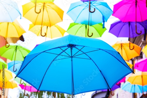 Umbrellas in the air . bright small streets of the city . Overcast weather . Rainy weather © yaalan
