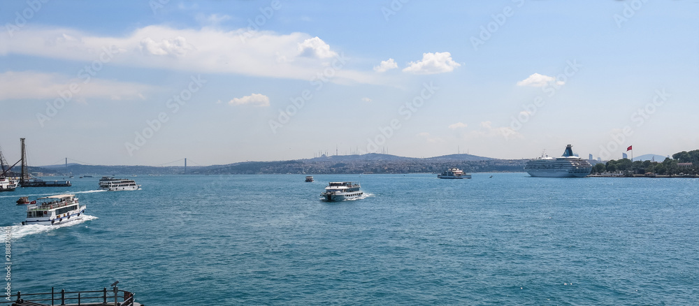 A tourist cruise, and several transport boats, travel the two banks of the Bosphorus in the city of Istanbul, Turkey