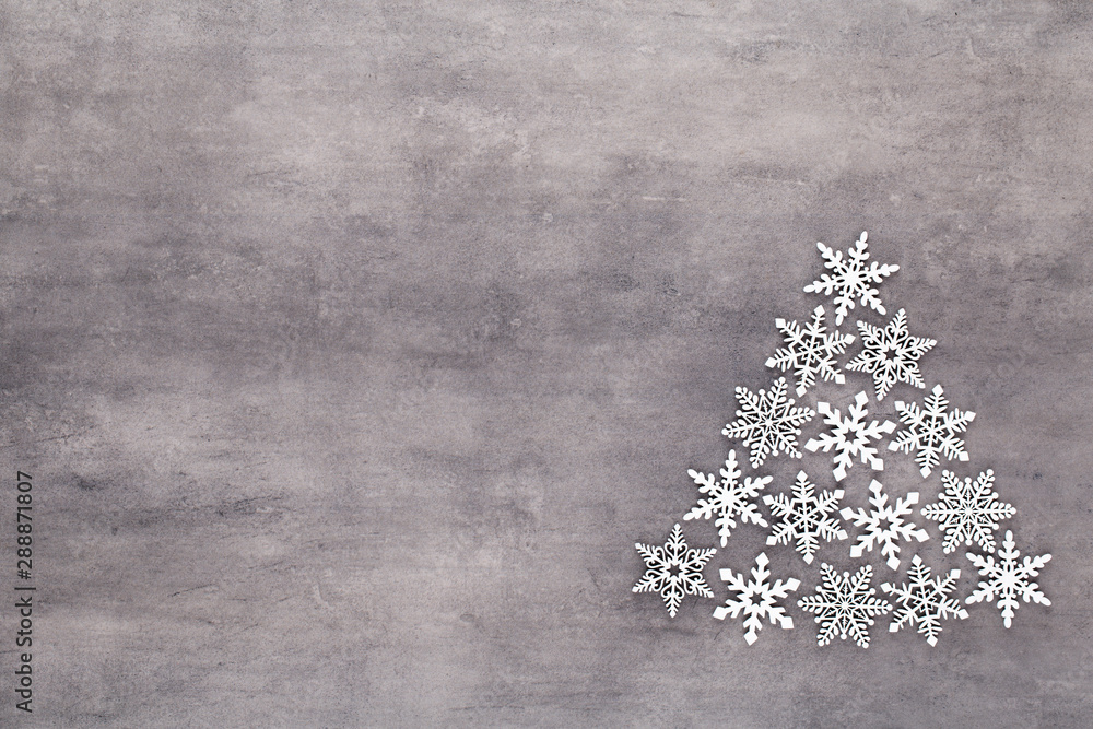 Christmas tree made from white snow flake decoration on gray background. Flat lay, top view Christmas tree made from white snow flake decoration on gray background. Flat lay, top view