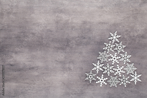 Christmas tree made from white snow flake decoration on gray background. Flat lay, top view