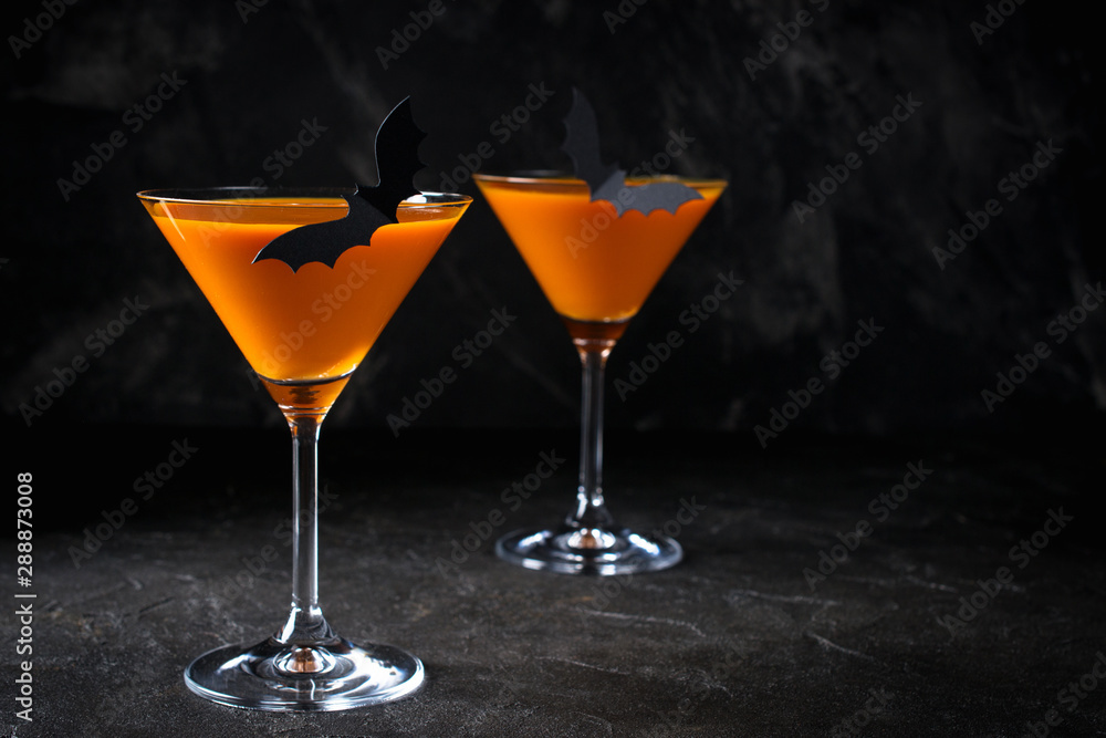 Orange pumpkin martini Halloween drink for party over black background with copy space Orange pumpkin martini Halloween drink for party over black background with copy space