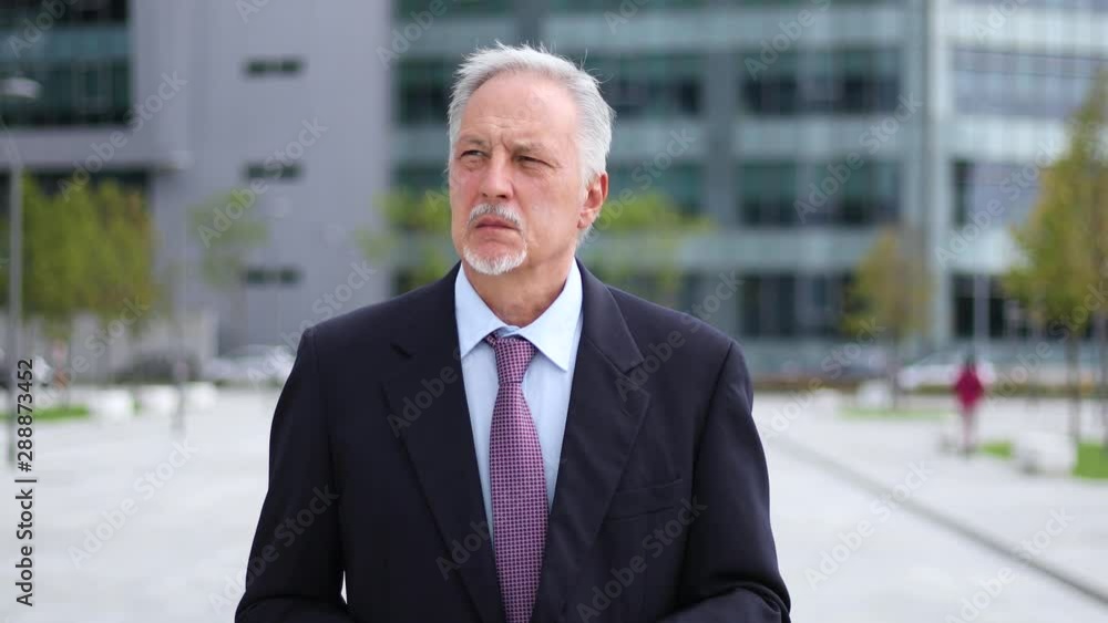 Mature businessman walking outdoor in a modern city setting Mature businessman walking outdoor in a modern city setting