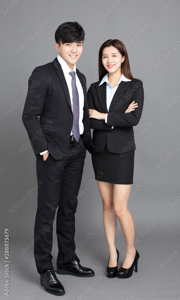 young business man and woman standing against gray background young business man and woman standing against gray background