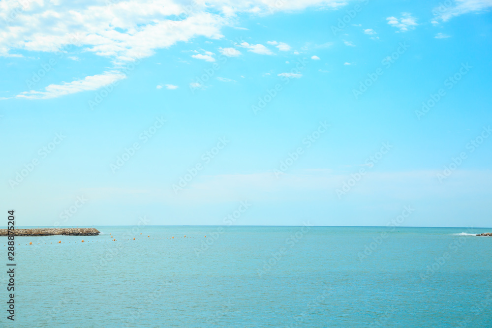 background of blue sky with beautiful clouds and a small part of the azure sea in the frame. the focus is selective.