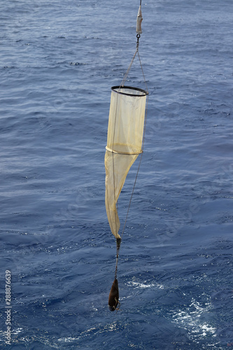 Plankton net on the blue water background. Science equipment for sampling of water organisms deployment.