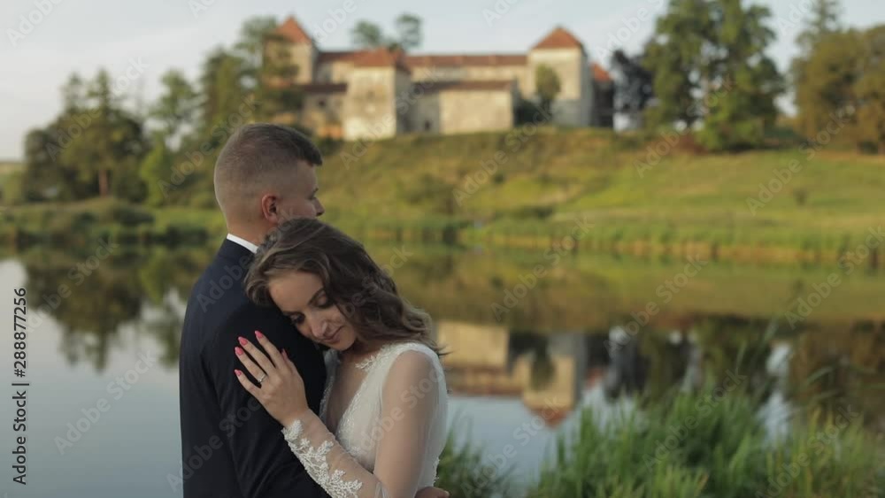 Caucasian groom with bride in the park near lake. Wedding couple. Newlyweds kiss Caucasian groom with bride in the park near lake. Wedding couple. Newlyweds kiss