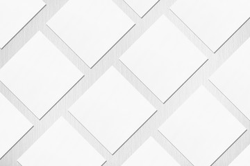 Many empty white square business card mockups with soft shadows lying diagonally on neutral light grey textured background. Flat lay, top view. Open composition.