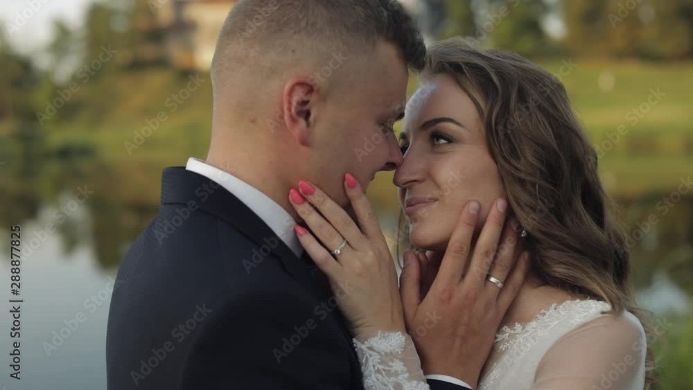 Caucasian groom with bride in the park near lake. Wedding couple. Newlyweds kiss Caucasian groom with bride in the park near lake. Wedding couple. Newlyweds kiss