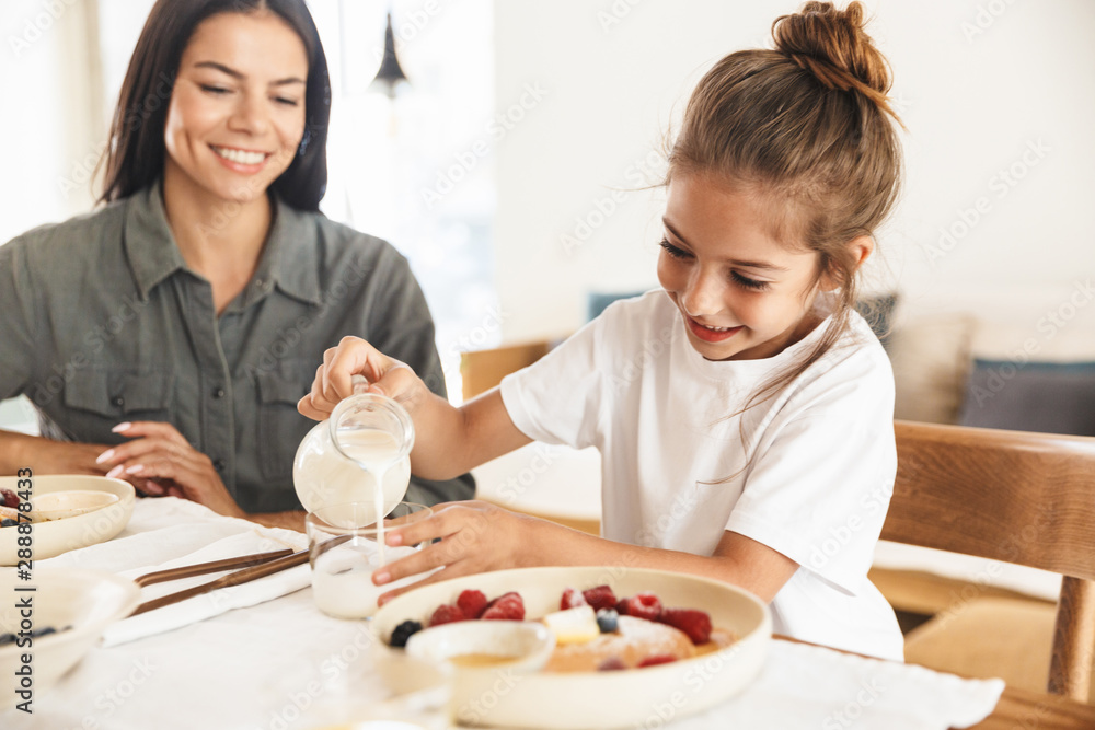 Image of lovely family mother and little daughter having breakfast at home in morning Image of lovely family mother and little daughter having breakfast at home in morning