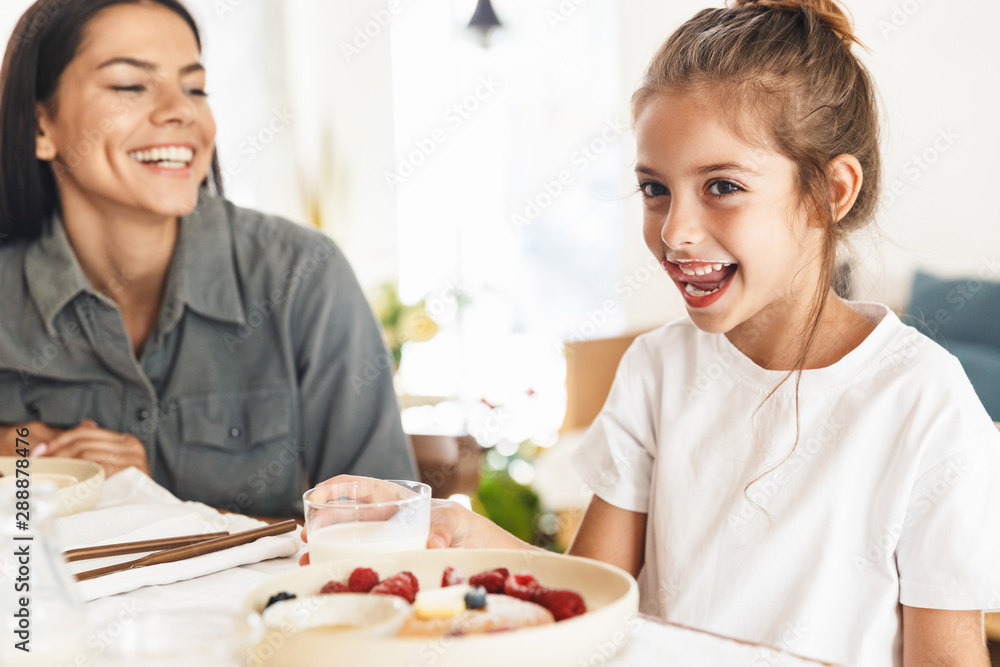 Image of amazing family mother and little daughter having breakfast at home in morning Image of amazing family mother and little daughter having breakfast at home in morning