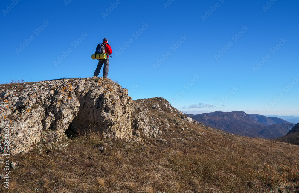 Photographer on top of the mountain in autumn. Traveler with backpack enjoying a view from the mountain top