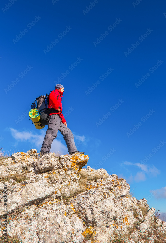 Photographer on top of the mountain in autumn. Traveler with backpack enjoying a view from the mountain top