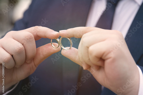 Hand of groom hold two engagement or wedding ring.