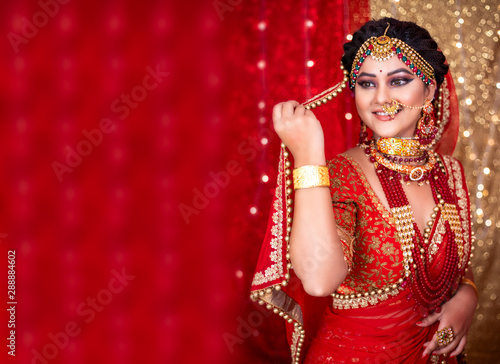 Tela Portrait of an Indian bride wearing traditional red lehanga with gold jewelry an