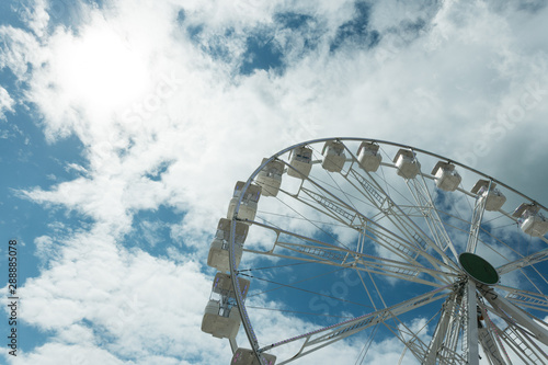 Ferris wheel on the blue cloudy sky. Background concept of happy holidays time. © sergiymolchenko