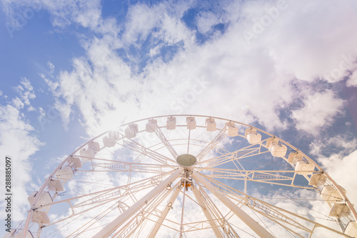 Ferris wheel on the colorful cloudy sky. Background concept of happy holidays time.