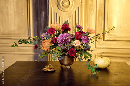 Happy Halloween pumpkin a copper vase with autumn flowers in the house. Romantic date getting ready for Halloween