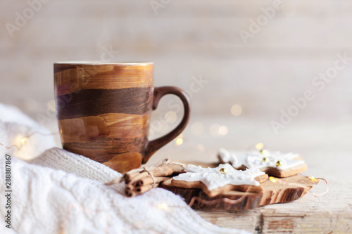 Christmas still life. Mug of hot steamy coffee, gingerbread cookies at wooden background with glares. Cozy morning breakfast with homemade sweets and cup of tea or cocoa. Winter drink, new year lights