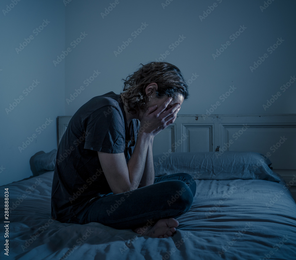 Desperate lonely teenager man suffering from depression sitting alone on bed Desperate lonely teenager man suffering from depression sitting alone on bed