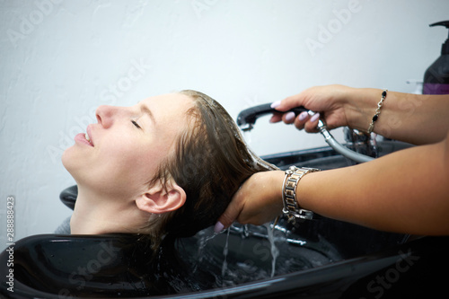 Hairdresser washing hair young man, who having pleasure and smiling. Hairstyle, beauty, treatment, hair care and repair concept.