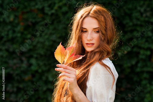 redhead girl autumn portrait with wild grape leaf