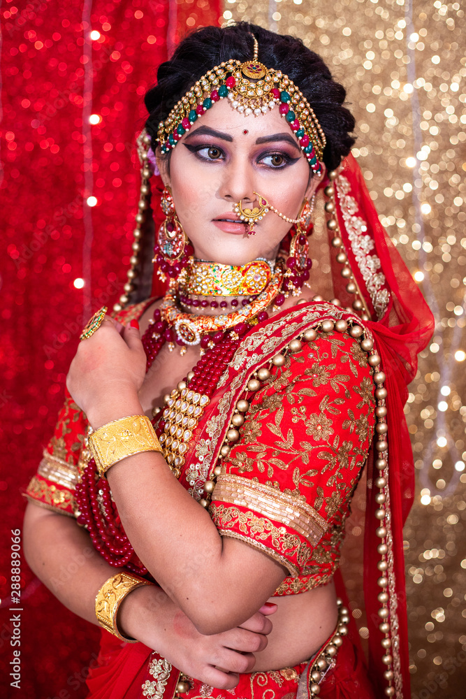 Portrait of a beautiful Indian model in Traditional bridal makeup with red  lehanga & heavy Gold and Diamond jewelry. Stock Photo | Adobe Stock