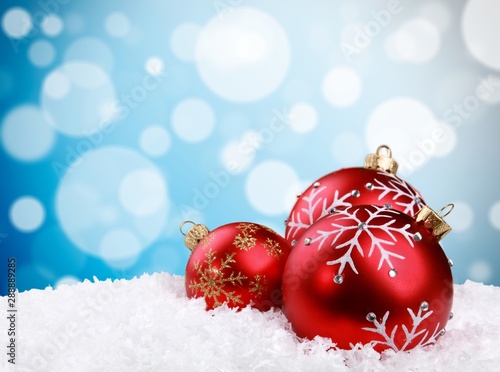 Red shiny decorative Christmas balls in snow on blurred background