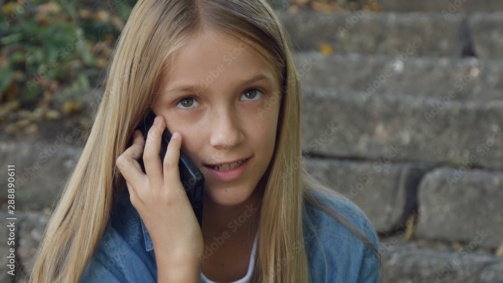 Child Talking on Smartphone, Kid Using Smart Phone, Girl Playing Outdoor in Park Child Talking on Smartphone, Kid Using Smart Phone, Girl Playing Outdoor in Park