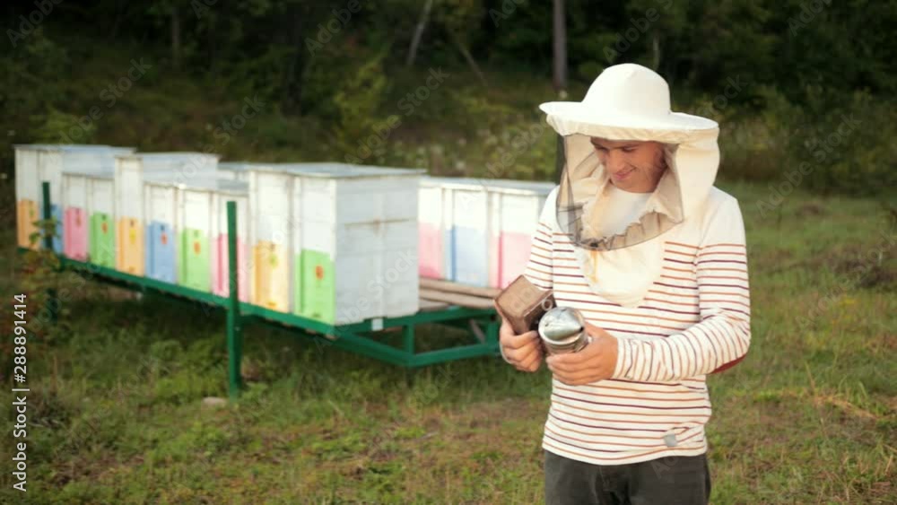 man beekeeper in special clothes, holding a smoker to calm the bees man beekeeper in special clothes, holding a smoker to calm the bees