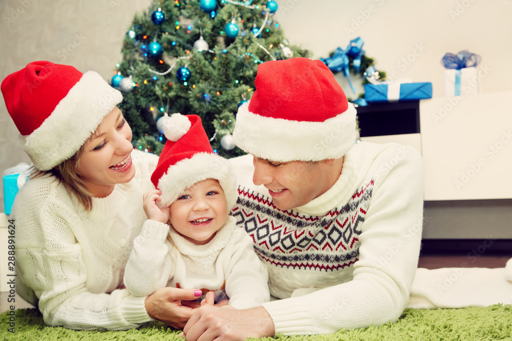 portrait of a young family. celebration at home. father, mother and child on the background of the Christmas tree. New Year and xmas people. portrait of a young family. celebration at home. father, mother and child on the background of the Christmas tree. New Year and xmas people.