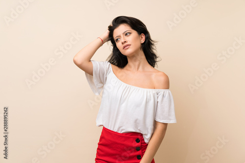 Young woman over isolated background having doubts while scratching head