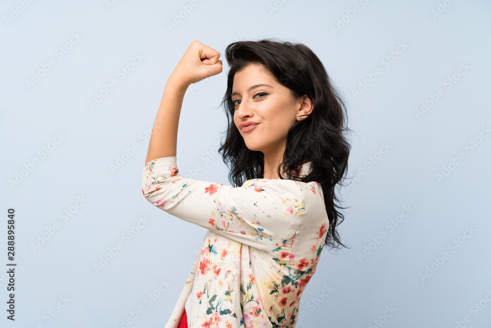 Young woman over isolated blue background making strong gesture Young woman over isolated blue background making strong gesture