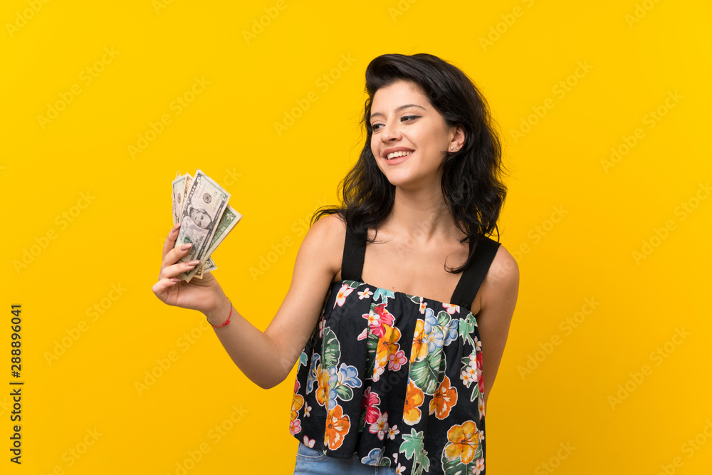 Young woman over isolated yellow background taking a lot of money Young woman over isolated yellow background taking a lot of money