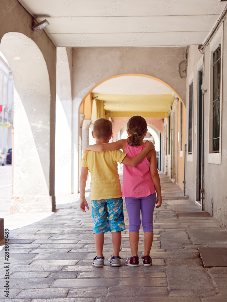 a boy with a girl are hugging along the street