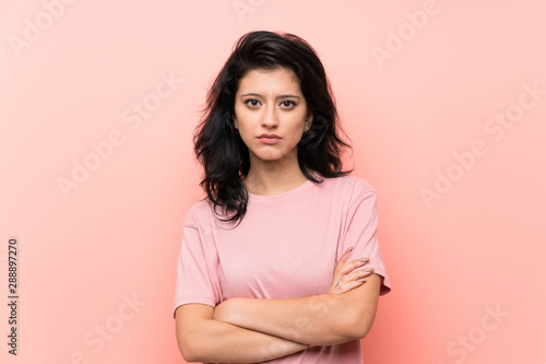 Young woman over isolated pink background keeping arms crossed