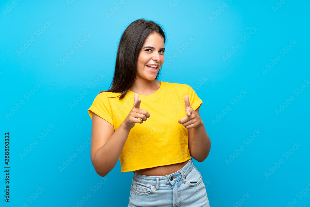 Young girl over isolated blue background pointing to the front and smiling Young girl over isolated blue background pointing to the front and smiling
