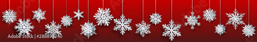 Christmas banner of large white complex paper hanging snowflakes on red background