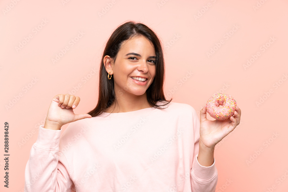 Young girl holding a donut over isolated pink background proud and self-satisfied Young girl holding a donut over isolated pink background proud and self-satisfied