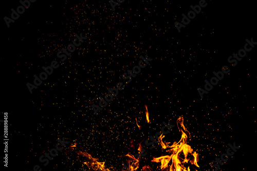 Burning red hot sparks fly from large fire in the night sky. Beautiful abstract background on the theme of fire, light and life.