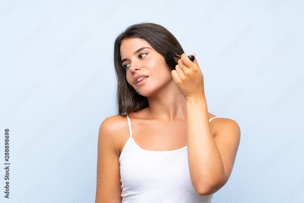 Young girl holding makeup brush over isolated background Young girl holding makeup brush over isolated background