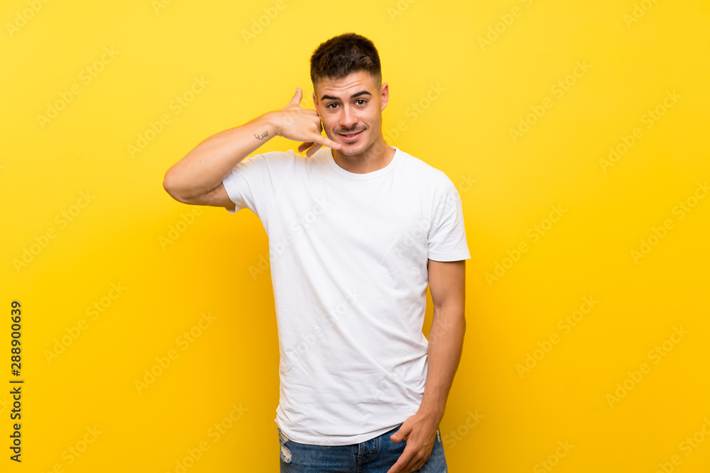 Young handsome man over isolated yellow background making phone gesture. Call me back sign Young handsome man over isolated yellow background making phone gesture. Call me back sign