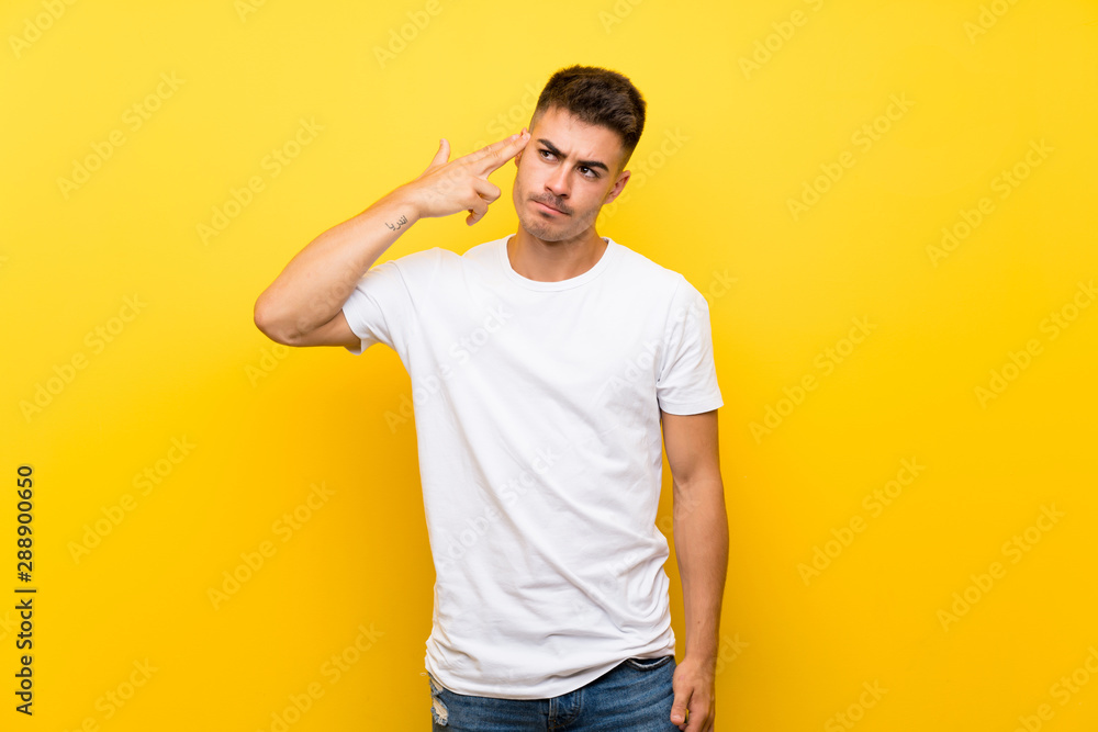 Young handsome man over isolated yellow background with problems making suicide gesture Young handsome man over isolated yellow background with problems making suicide gesture