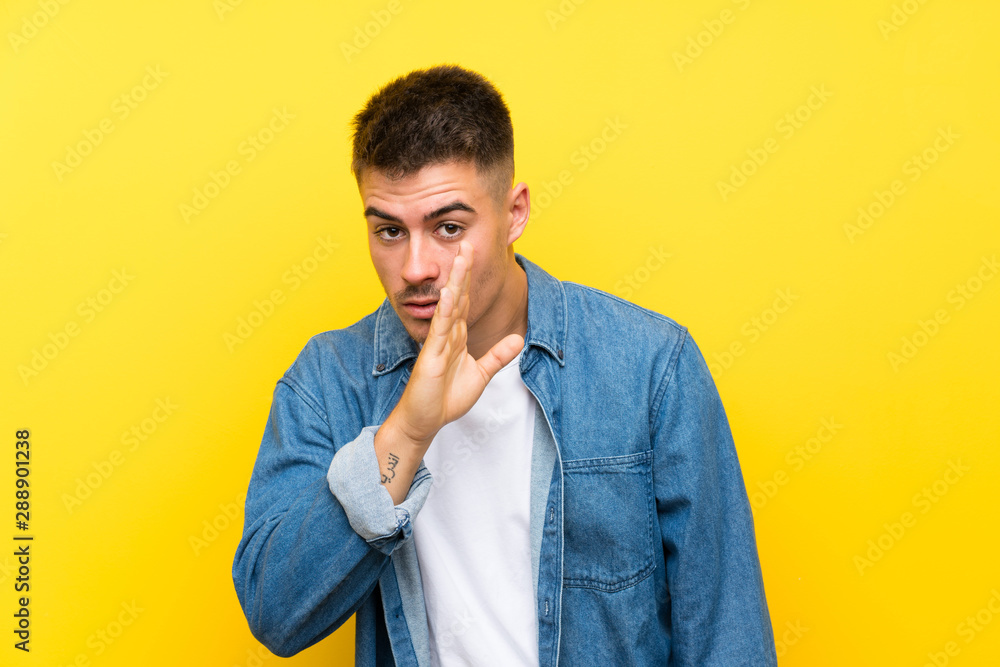 Young handsome man over isolated yellow background whispering something Young handsome man over isolated yellow background whispering something