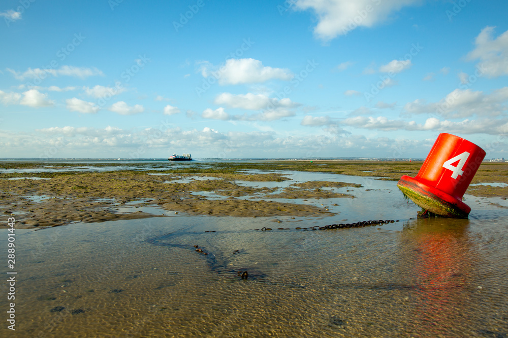 Naklejka premium Marine traffic: red buoy on the foreshore with hovercraft in the background