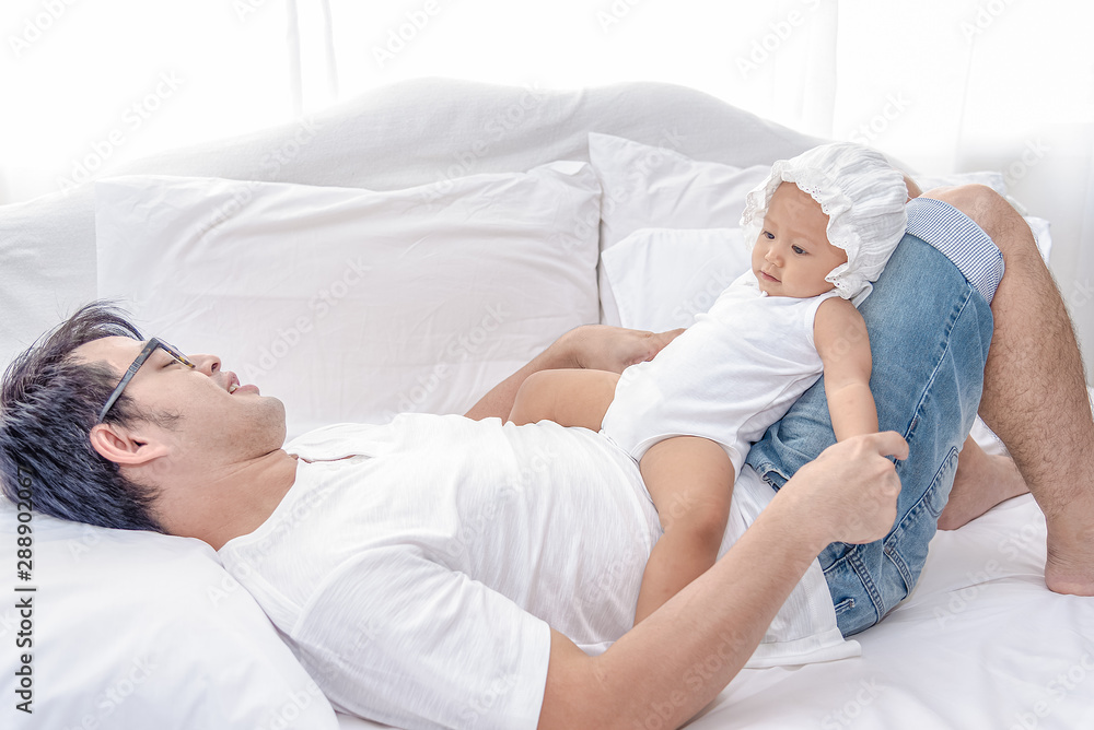Fototapeta premium Daddy and little baby daughter tired after playing together. Father takes are of his little girls on the weekend.