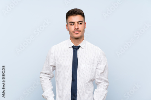 Handsome businessman over isolated blue background standing and looking to the side