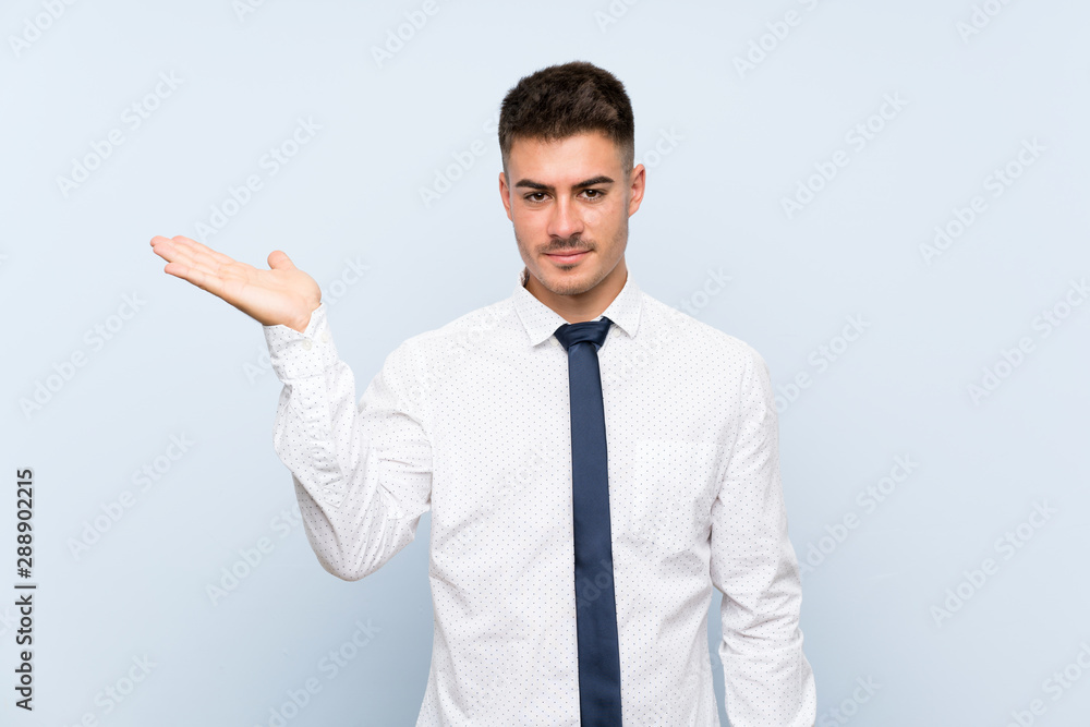 Handsome businessman over isolated blue background holding copyspace imaginary on the palm Handsome businessman over isolated blue background holding copyspace imaginary on the palm